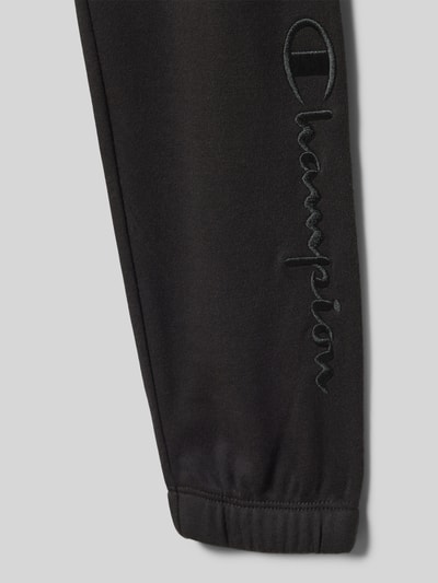 Produktfoto, schwarze Sweatpants mit elastischem Bund von CHAMPION, Baumwoll-Mix, sichtbarer Logo-Schriftzug, Detailaufnahme.