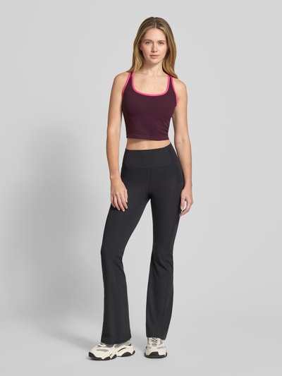 Frauenmodel trägt Cropped Top mit integriertem Bustier von Fabletics in Lila mit pinken Details, Elastischer-Material-Mix, Rückenausschnitt und Rücklenlänge von 13 cm, Ganzkörperansicht von vorne.