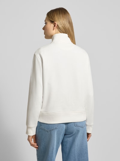 Modelka nosi Bluza 'Sweatshirt mit Baumwoll-Anteil' od Gant, mieszanka bawełny, luźny krój, kołnierz zapinany, wyhaftowane logo, prążkowane wykończenia, widok całej sylwetki z tyłu.