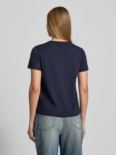 Kobiece modelka ma na sobie granatowy T-Shirt mit Label-Print und Rundhalsausschnitt od Gant, bawełna, regular fit, widok cała sylwetka od tyłu.