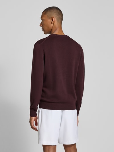 Männermodel trägt Regular Fit Pullover aus Baumwoll-Mix von Lacoste in Dunkelrot zu weißen Shorts, Ganzkörperansicht Rückansicht. Herren Pullover von Lacoste.