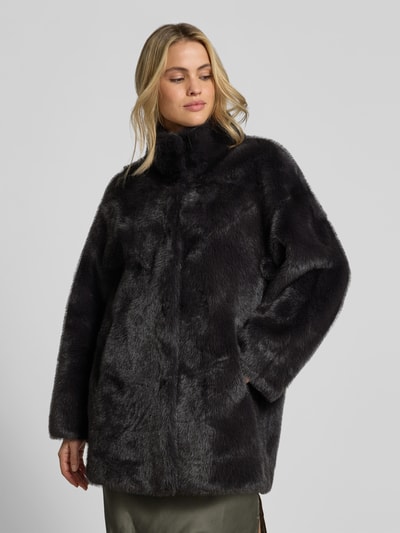 Modelka nosi Wendemantel aus Kunstfell od Juvia w czerni, prosty krój, stójka, kieszenie, detailowe tekstury futerka, widok z przodu, Ganzkörperansicht von vorne. Szerokość w rozmiarze S: 53 cm, długość tyłu: 80 cm, długość rękawa: 64 cm.
