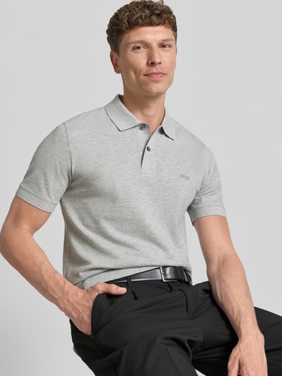 Männermodel trägt Regular Fit Poloshirt aus reiner Baumwolle Modell 'PALLAS' von BOSS in Optik: Unifarben, Nahaufnahme Oberkörper. Label-Stitching-Applikation, Polokragen, V-Ausschnitt, kurze Knopfleiste, Ärmelform: Kurzarm, Ärmelabschluss: Gerippt, Rumpfabschluss: mit Seitenschlitzen, Materialverarbeitung: Piqué.