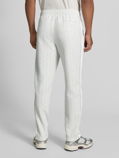 Männermodel trägt Regular Fit Sweathose mit Baumwoll-Anteil von Lacoste in Weiß mit dezenter Musterstruktur, Ganzkörperansicht Rückansicht.