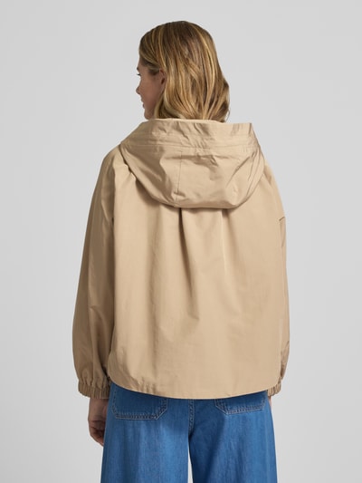 Frauenmodel trägt Relaxed Fit Regenjacke mit Baumwoll-Anteil Modell 'ROMANA' von Weekend Max Mara in Beige, Kapuze, elastische Ärmelabschlüsse, seitliche Eingrifftaschen, wasserabweisend, Ganzkörperansicht Rückansicht.