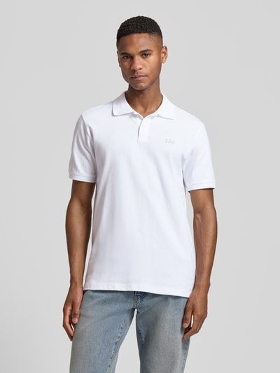 Männermodel trägt Slim Fit Poloshirt mit Label-Stitching von GAP in Weiß, Baumwoll-Elasthan-Mix, Knopfleiste, Ganzkörperansicht von vorne.