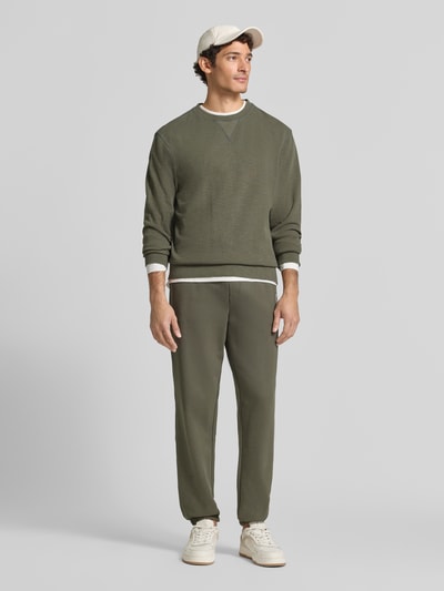 Männermodel trägt Sweatpants mit elastischem Bund und Tunnelzug von Scotch & Soda, Baumwolle, Regular Fit, Logo, Ganzkörperansicht von vorne.