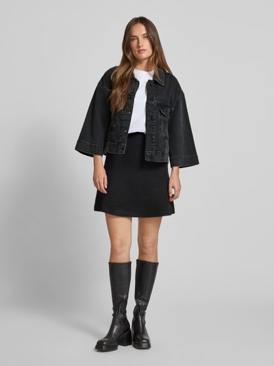 Frauenmodel trägt Jeansjacke mit weiten Ärmeln Modell 'Penn Deluxe' von MOS MOSH, schwarzer Baumwoll-Lyocell-Mix, lockerer Schnitt, Umlegekragen, Brusttaschen, Ganzkörperansicht von vorne.