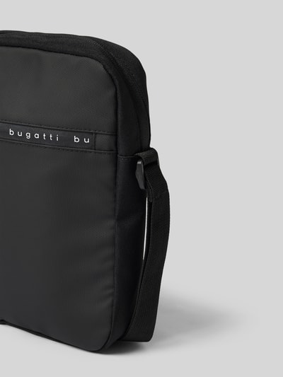 Produktfoto, czarna Umhängetasche mit Label-Details Modell 'Blanc Delight' von bugatti, struktura materiału, kontekst: torba męska, główna komora na zamek, regulowany pasek na ramię, szerokość w rozmiarze 1: 21 cm, długość w rozmiarze 1: 26 cm, głębokość w rozmiarze 1: 5 cm, długość paska w rozmiarze 1: 118 cm