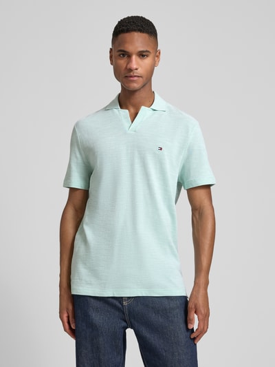 Männermodel trägt Regular Fit Poloshirt aus reiner Baumwolle von Tommy Hilfiger, Melange-Optik, Logo-Stitching, Ganzkörperansicht von vorne.