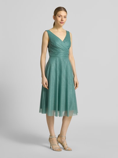 Frauenmodel trägt knielanges Cocktailkleid mit V-Ausschnitt von TROYDEN COLLECTION aus Chiffon in Taillierter Schnitt und Breite Träger, Ganzkörperansicht von vorne.