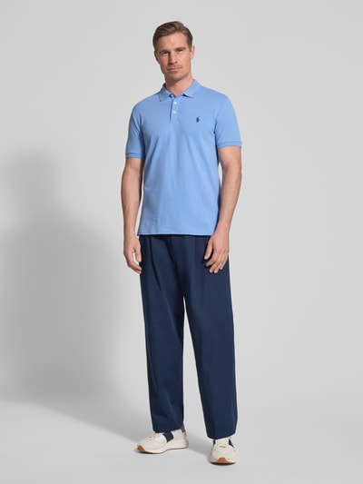 Männermodel trägt lichtblauw Slim Fit Poloshirt aus Baumwoll-Mix van Polo Ralph Lauren, look: effen, piqué structuur, logodetail, korte mouw, polokraag, geribde mouwboord, asymmetrische rompzoom, Ganzkörperansicht van voren.
