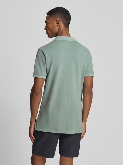 Männermodel trägt Slim Fit Poloshirt mit Label-Stitching von GAP in Grün, Baumwoll-Elasthan-Mix, Ganzkörperansicht Rückansicht.