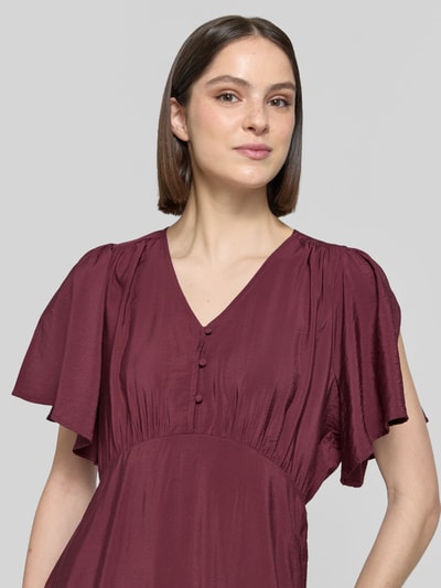 Frauenmodel trägt Midikleid aus Viskose-Mix mit V-Ausschnitt Modell 'Aniva' von ICHI in Weinrot, taillierte Passform, Knopfleiste, Kurzärmelig, Nahaufnahme Oberkörper. Kontext: Rückenlänge bei Größe 36: 116 cm, Brustweite: 34 cm, Ärmellänge: 26 cm.
