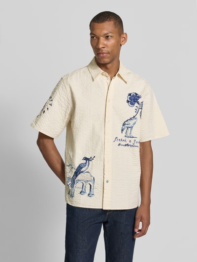 Männermodel trägt Relaxed Fit Freizeithemd aus reiner Baumwolle von Scotch & Soda, kurzärmelig, Strukturmuster, Motiv-Stitching, Ganzkörperansicht von vorne