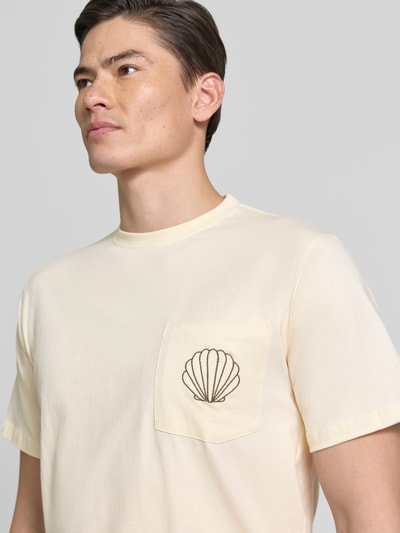 Männermodel trägt T-Shirt mit Brusttasche und Stitching Modell 'Ilfracombe' von BOARDIES in Creme, reine Baumwolle, Nahaufnahme Oberkörper.