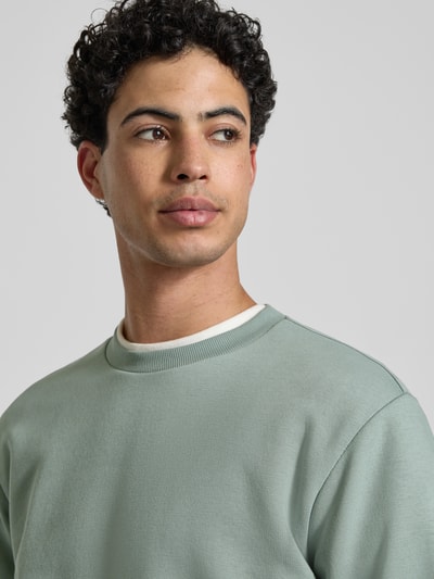Männermodel trägt Regular Fit Sweatshirt aus Baumwoll-Mix Modell 'CERES' von Only & Sons in Unifarbe mit Rundhals, Nahaufnahme Oberkörper.