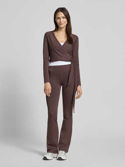 Kobiece modelka nosi Cropped Wickelshirt mit V-Ausschnitt od aim'n z mieszanki materiałów z dodatkiem streczu, krój krótki, bluzka z długim rękawem, dekolt w serek, długość tyłu w rozmiarze S: 40 cm, widok całej sylwetki z przodu