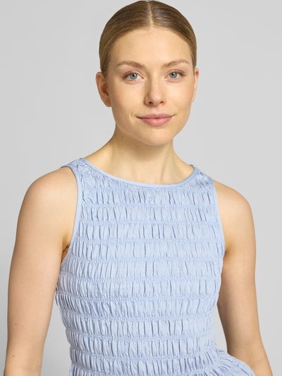 Frauenmodel trägt Slim Fit T-Shirt aus Viskose-Mix Modell 'NORI SMOCK' von Vero Moda in Hellblau, Strukturmuster, ärmellos, Nahaufnahme Oberkörper.