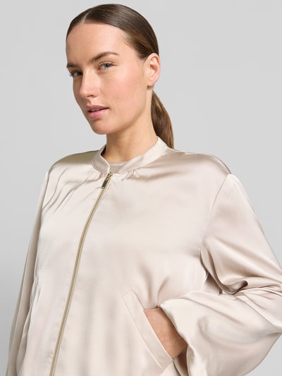 Frauenmodel trägt Regular Fit Blazer aus Satin mit Reißverschluss von Betty Barclay in hellbeige Satin-Optik, Eingrifftaschen, Nahaufnahme Oberkörper, Rückenlänge 50 cm, Brustweite 56 cm, Ärmellänge 58 cm, Größe 36.