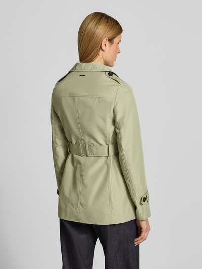 Frauenmodel trägt Regular Fit Trenchcoat aus Baumwoll-Mix von s.Oliver RED LABEL in hellem Grün, unifarben, Rückenpasse, Ganzkörperansicht Rückansicht.