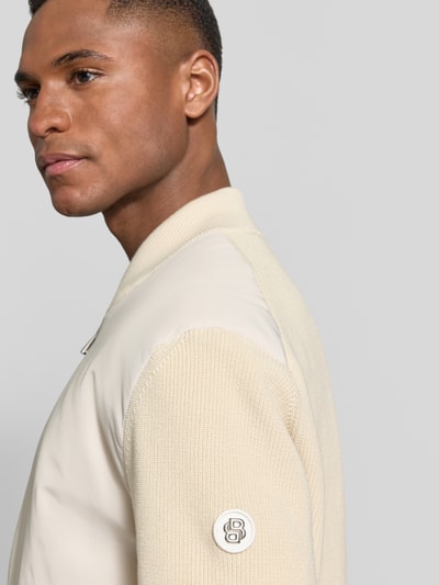 Männermodel trägt Regular Fit Strickjacke aus Baumwoll-Mix Modell 'C-UBAIO' von BOSS in Beige mit Logo-Patch, Nahaufnahme Oberkörper.