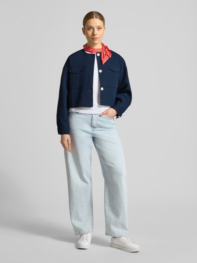Frauenmodel trägt Boxy Fit Kurzblazer aus Viskose-Mix von Tommy Hilfiger in Optik: Unifarben, Passform: Boxy-Fit, Rundhals-Ausschnitt, Cropped, Logo-Stitching, einreihige Knopfleiste, Langarm mit Manschette, Brustpattentaschen, Material: Viskose-Mix, dunkles Blau vor hellem Hintergrund, glatte und strukturierte Stoffoptik; Ganzkörperansicht von vorne.