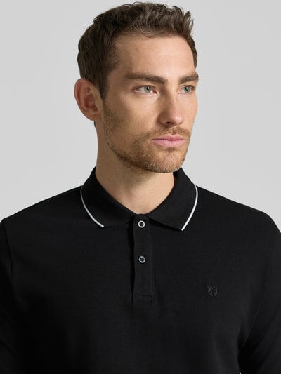 Męski model nosi Slim Fit Poloshirt mit Stitching von Jack & Jones Premium, czarna bawełna, listwa guzikowa, krój slim fit, haft, długość tyłu 70 cm w rozmiarze M, zbliżenie na górną część ciała z przodu