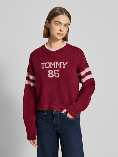 Kobiece model prezentuje Oversized Strickpullover mit Woll-Anteil od Tommy Jeans, sweter dzianinowy, kolor jednolity, nadruk z przodu, długi rękaw, wykończenia ściągaczowe, widok całej sylwetki z przodu.