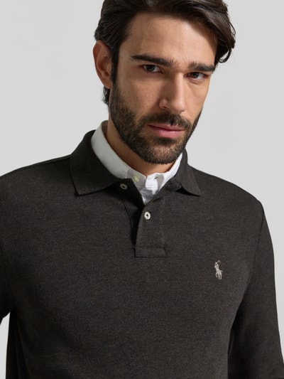 Männermodel trägt Poloshirt mit Label-Stitching von Polo Ralph Lauren, reine Baumwolle, Knopfleiste, dunkel, Nahaufnahme Oberkörper.