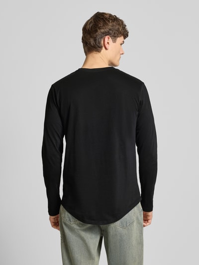 Męski model nosi Longsleeve mit geripptem Rundhalsausschnitt Modell 'ENOA' von JACK & JONES, czarny bawełniany regular fit, zaokrąglony dół, widok całej sylwetki od tyłu.