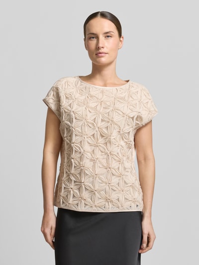 Frauenmodel trägt Regular Fit Kurzarmbluse mit 3D-Effekt von s.Oliver BLACK LABEL in Beige mit Chiffon-Besatz, U-Boot-Ausschnitt, Ganzkörperansicht von vorne.
