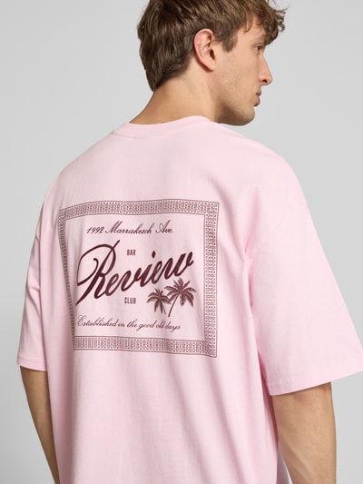 Männermodel trägt T-Shirt mit Rundhalsausschnitt und Label-Print von REVIEW, Reine Baumwolle, Relaxed-Fit, Rückenlänge 71 cm, Ganzkörperansicht Rückansicht.