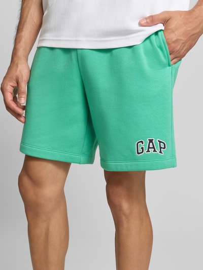 Männermodel draagt Straight Fit Shorts met logo-Stitching model 'Heritage' van GAP in groen katoenmix, binnenbeenlengte 20 cm, bandwijdte 40 cm, elastische band met tunnelkoord, nahaufnahme bovenbenen.