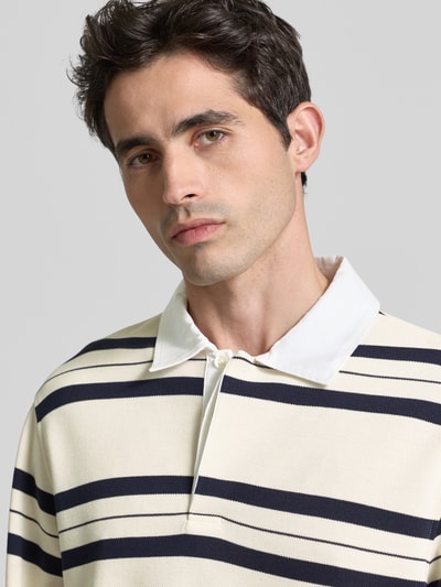 Męski model nosi Regular Fit Poloshirt mit Streifenmuster von GUESS, mieszanka materiałów z dodatkiem wiskozy, kołnierzyk polo, bluzka z długim rękawem, wzór w paski, długość tyłu w rozmiarze M: 71 cm, długość rękawów: 72 cm, zbliżenie na górną część ciała