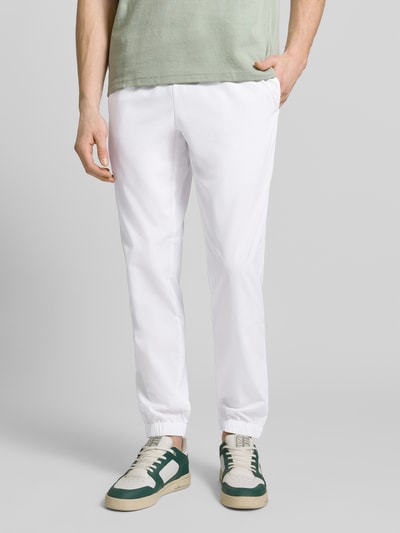 Männermodel trägt Regular Fit Trainingsanzug mit Logo-Detail von Lacoste Sport, unifarben weiß, Sweat-Stoff, Nahaufnahme Unterkörper.