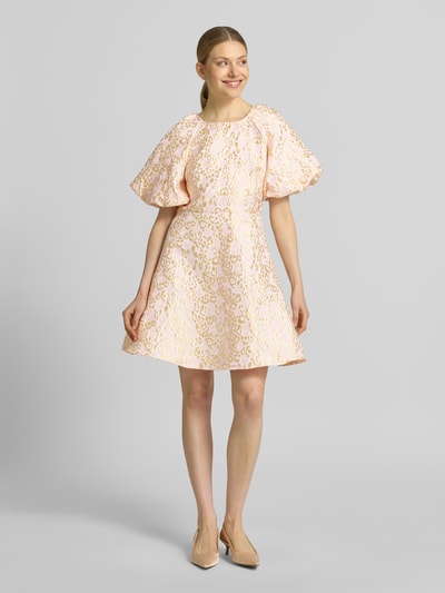 Vrouwenmodel draagt tailliertes cocktailjurk met all-over motief model 'NORA' van Vero Moda, mini-lengte, ronde hals, pofmouwen, striksluiting, rugdecolleté, lichte tinten, structuurstof, pasvorm: getailleerd. Ganzlichaamsaanzicht van voren.