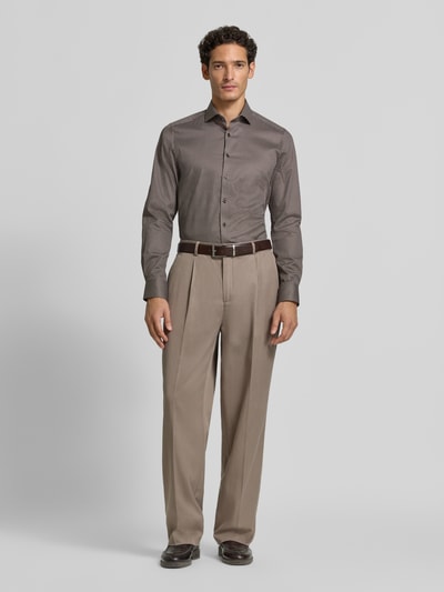 Männermodel trägt Body Fit Businesshemd aus Baumwoll-Mix von OLYMP Level 5, feines Muster in Braun, glatte Textur, Ganzkörperansicht von vorne.