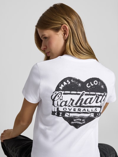 Frauenmodel trägt T-Shirt mit Label-Detail von Carhartt Work In Progress in Weiß, reine Baumwolle, gerader Schnitt, Rückenlänge 49 cm, Ganzkörperansicht Rückansicht.