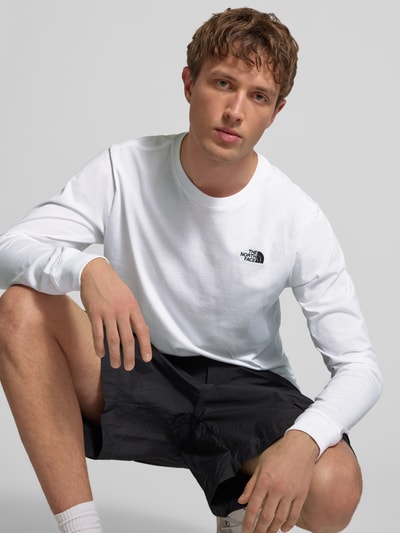 Männermodel trägt Longsleeve mit Label-Stitching von The North Face aus Baumwoll-Mix, weiß, Regular Fit, Nahaufnahme Oberkörper.