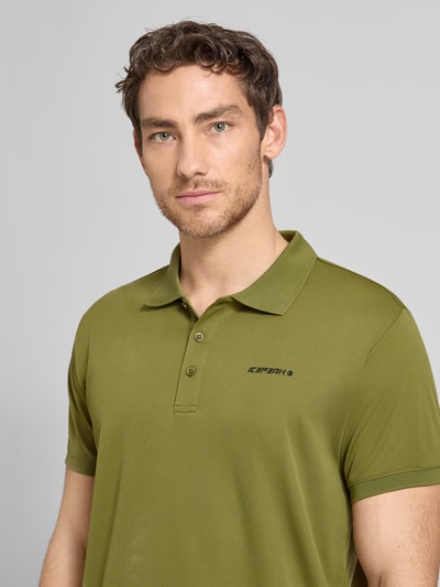 Männermodel trägt Regular Fit Poloshirt mit Logo-Print Modell 'BELLMONT' von Icepeak in Olivgrün, Kurzärmelig, Nahaufnahme Oberkörper.