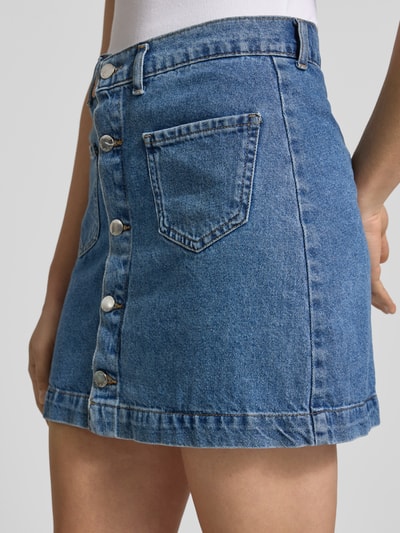 Frauenmodel trägt Schmaler Jeansrock aus reiner Baumwolle Modell 'AMAZING' von Only in Denim-Optik mit Kontrastnaht, Mini-Länge, Nahaufnahme Oberkörper.
