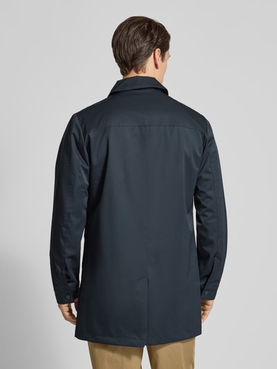 Męski model nosi Krótki płaszcz z wykładanym kołnierzem i detalem z logo model 'EIDE' od Casual Friday, mieszanka materiałów z dodatkiem streczu, krój regular fit, wpuszczana kieszeń, kolor ciemnogranatowy, Długość tyłu w rozmiarze M: 88 cm, Szerokość ramion w rozmiarze M: 46 cm, Szerokość klatki piersiowej w rozmiarze M: 54 cm, Długość rękawów w rozmiarze M: 66 cm, widok całej sylwetki z tyłu.
