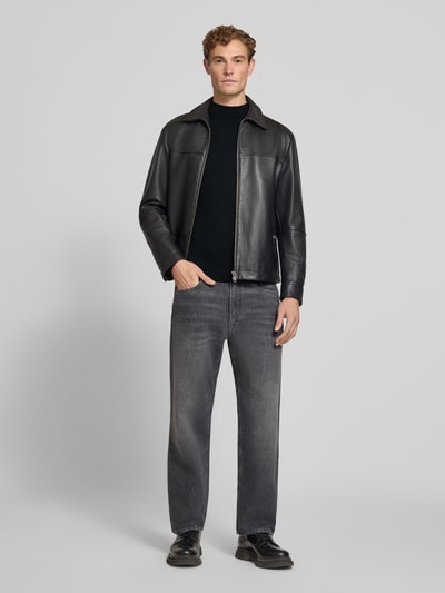 Männermodel trägt Slim Fit Longsleeve aus reiner Schurwolle Modell 'Arwon' von DRYKORN in Schwarz, glatte Textur, Ganzkörperansicht von vorne.