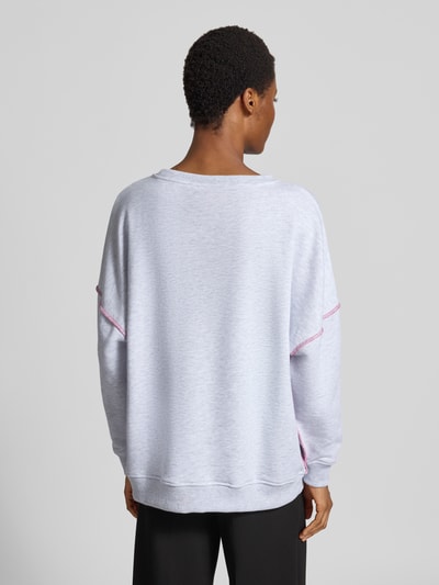 Frauenmodel trägt Oversized Fit Sweatshirt aus reiner Baumwolle von miss goodlife in Hellgrau mit Pailettenbesatz, Statement-Print, elastische Abschlüsse, Ganzkörperansicht Rückansicht.