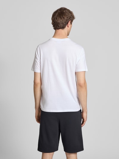 Männermodel trägt T-Shirt mit Label-Print und Rundhalsausschnitt von CHAMPION in Weiß, reine Baumwolle, Regular Fit, Rückansicht Ganzkörperansicht.