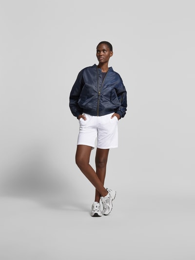 Frauenmodel trägt Sweatshorts aus Baumwoll-Mix von Juvia in Weiß mit Gerader Passform, elastischem Bund mit Tunnelzug, Eingrifftaschen, breiter Bund, Ganzkörperansicht von vorne.