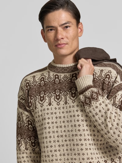 Männermodel trägt Regular Fit Pullover aus reiner Wolle Modell 'Albertville' von Dale of Norway, beige-braunes Norwegermuster, Nahaufnahme Oberkörper. Rückenlänge bei Größe M 66 cm, Ärmellänge 59 cm, Strick-Optik.