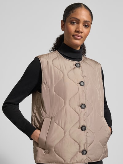 Frauenmodel trägt Regular Fit Steppweste mit einreihiger Knopfleiste Modell 'MILLIE' von Vero Moda, Optik: Unifarben, seitliche Eingrifftaschen, Materialverarbeitung: Stepp, Ganzkörperansicht von vorne.