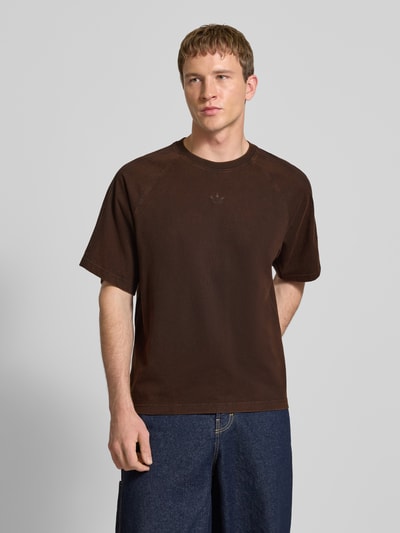 Männermodel trägt T-Shirt mit Rundhalsausschnitt und Label-Stitching von adidas Originals, Reine Baumwolle, Relaxed-Fit, Ganzkörperansicht von vorne.